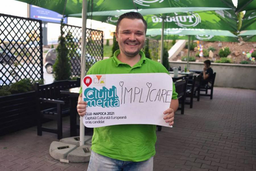 Razvan Dragoș cu o pancartă pe care scrie Clujul Merită IMPLICARE